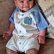 Caolán joined the competition — help win amazing prizes! baby, child, smiling, couch, pillow, onesie, clothing, infant, cute, happy, sitting, indoor, portrait, soft_furniture, patterned_pillow, person, young_child, sock, casual, relaxed