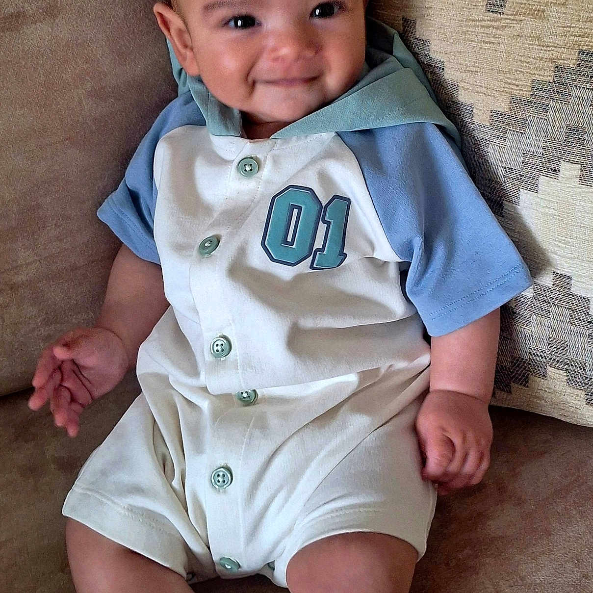 Caolán joined the competition — help win amazing prizes! baby, casual, child, clothing, couch, cute, happy, indoor, infant, onesie, patterned_pillow, person, pillow, portrait, relaxed, sitting, smiling, sock, soft_furniture, young_child