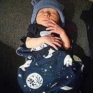 Abel is registered to the contest to win money with this photo: baby, blanket, child, clothing, cozy, cute, dark_background, fabric, hands, hat, indoor, infant, newborn, peaceful, person, portrait, resting, sleeping, soft, wrapped