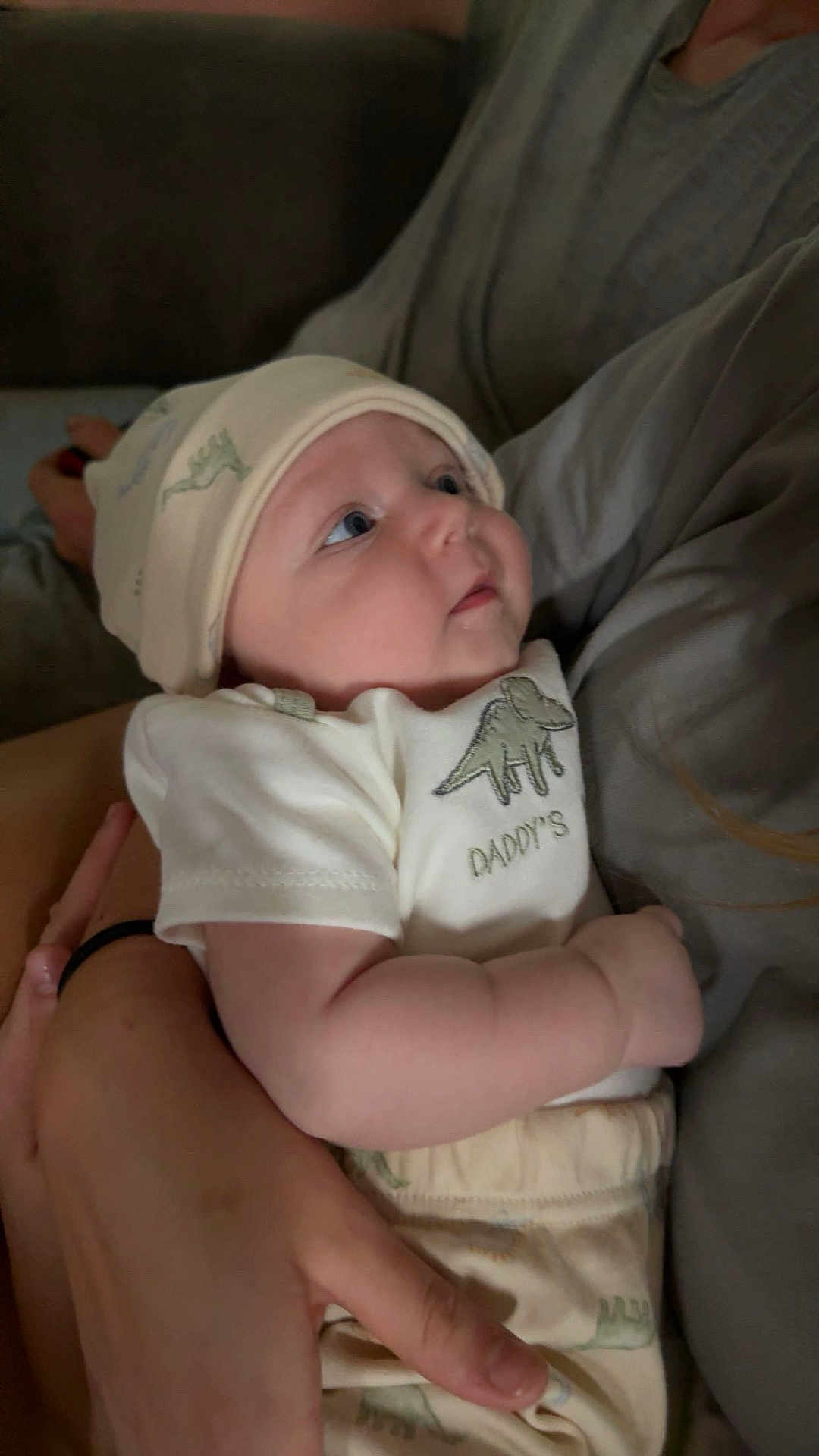 Easton is registered to the contest to win money with this photo: baby, infant, child, hat, dinosaur, clothing, arms, person, holding, cute, soft, looking, indoors, apparel, young, portrait, skin, hand, sleepwear, comfort
