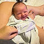 Easton is registered to the contest to win money with this photo: baby, smiling, infant, blanket, hand, legs, bed, bottle, clothing, person, indoor, cute, newborn, skin, holding, comfort, rest, nail_polish, cozy, family