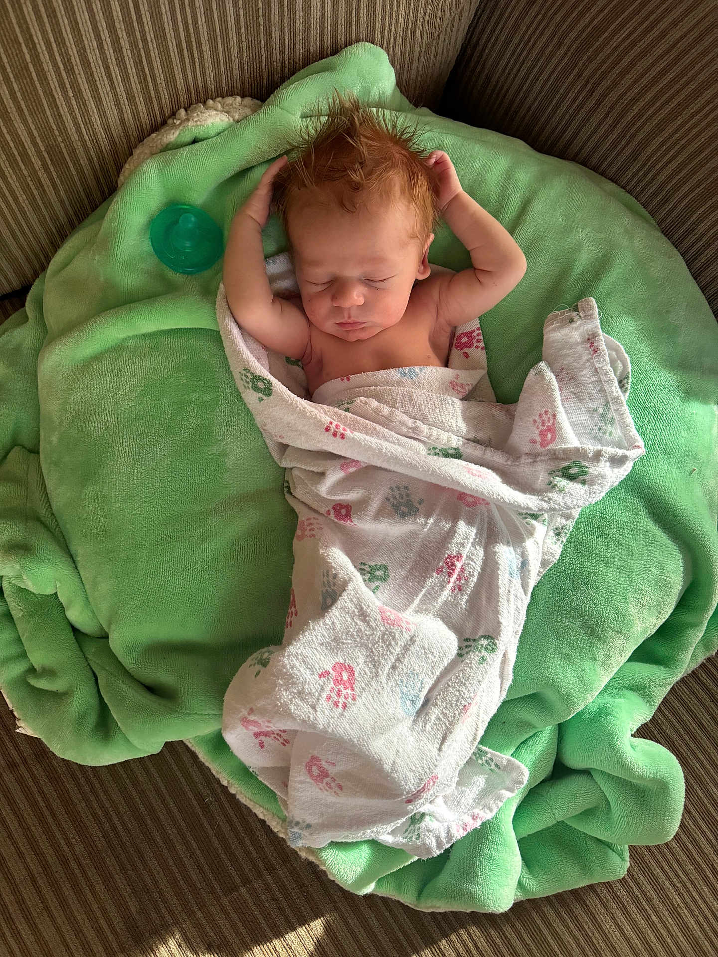 Riott is registered to the contest to win money with this photo: baby, newborn, sleeping, blanket, green_blanket, pacifier, couch, striped_couch, infant, wrapped, peaceful, soft_texture, indoors, natural_light, child, person, cute, relaxing, home, portrait