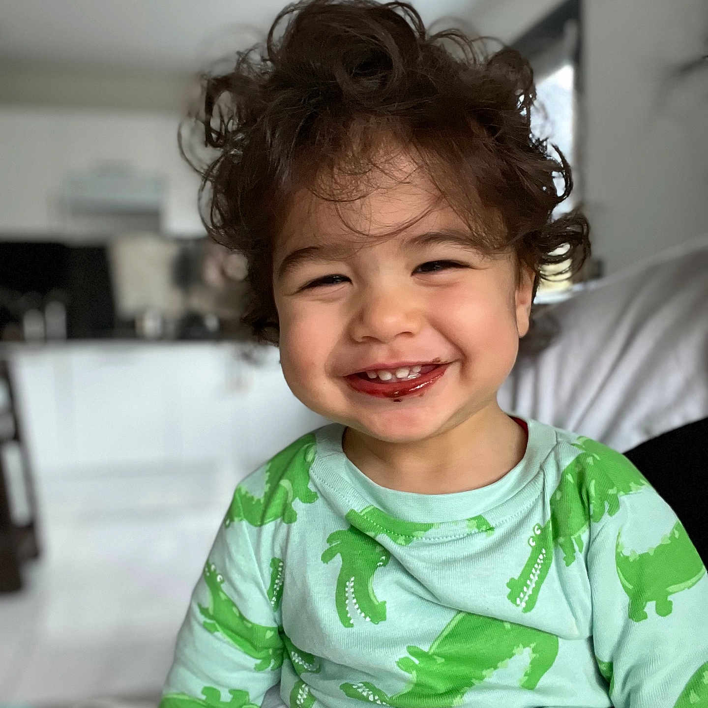 Aslann a rejoint le concours — aidez-le/la à gagner de superbes lots ! baby, blurred_background, casual_clothing, child, chocolate, cozy, crocodile_pattern, curly_hair, cute, face, green_shirt, hand, happy, indoor, person, playful, portrait, sitting, smile, toddler