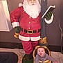 Theo is registered to the contest to win money with this photo: baby, child, santa_claus, statue, indoor, holiday, decorative, gold, red, white_beard, book, smiling, face, person, floor, clothing, festive, expression, toy, cute