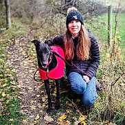 Sadie joined the competition — help win amazing prizes! autumn, beanie, dog, fallen_leaves, field, grass, greyhound, jacket, jeans, kneeling, leash, nature, outdoors, path, person, pet_owner, portrait, red_coat, smiling, trees