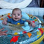 baby, blue_clothing, child, colorful, cute, face, floatation_device, fun, hand, indoor_pool, infant, inflatable_ring, person, playful, pool, safety, smiling, swimming, toy, water