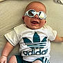 Eden a rejoint le concours — aidez-le/la à gagner de superbes lots ! adidas, baby, casual, child, clothing, cute, face, fashion, happy, head, indoor, infant, person, reflection, relaxed, shorts, sitting, smiling, sunglasses, tshirt