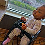 Icslyn is registered to the contest to win money with this photo: baby, child, high_chair, pajamas, indoor, window, food, eating, floor, table, sock, person, face, furniture, cute, expression, hand, seat, footwear, room