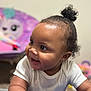 baby, child, smiling, white_onesie, curly_hair, pony_tail, indoor, toys, purple_chair, cute, happy, face, person, infant, playroom, soft_focus, background_blur, cheerful, close_up, skin