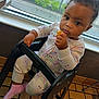 baby, child, high_chair, pajamas, snack, indoor, window, floor_tiles, curly_hair, expression, person, seat, pink_socks, food, hand, face, looking, young_child, cute, furniture