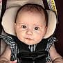 baby, infant, car_seat, harness, buckle, head_support, wide_eyes, chubby_cheeks, striped_clothing, hands, pacifier_clip, wooden_clip, warning_label, portrait, close_up, seat_padding, skin, young_child, cute_expression, blue_eyes