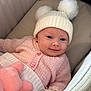 Marnie is registered to the contest to win money with this photo: baby, infant, child, smile, hat, pom_poms, knitwear, pink_sweater, plush_toy, cushion, comfort, cozy, cute, indoor, portrait, soft_lighting, hand, face, happy, closeup