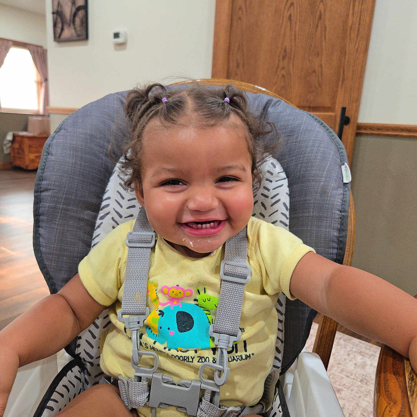 Wrenleigh joined the competition — help win amazing prizes! toddler, child, high_chair, smiling, happy, baby, indoors, wood, hair, pigtails, clothing, seatbelt, furniture, face, person, room, window, curtain, table, shirt