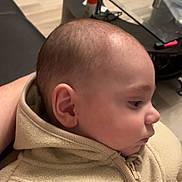 Soa participe au concours pour gagner de l'argent avec cette photo : baby, infant, profile, face, ear, clothing, jacket, beige, fleece, indoor, table, glass, floor, wooden_floor, person, young_child, cozy, seated, closeup, home