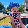 arms, baby, blue_sky, car, child, clothing, grass, happy, headband, holding, house, legs, outdoor, pattern, person, smile, stars, stripes, sunny, tree