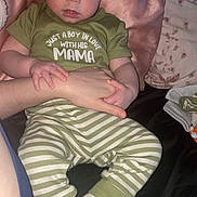 Alexander joined the competition — help win amazing prizes! baby, child, infant, person, clothing, green_shirt, striped_pants, socks, hand, pillow, blanket, bed, indoor, cute, holding, expression, face, young, rest, comfort