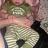 baby, child, infant, person, clothing, green_shirt, striped_pants, socks, hand, pillow, blanket, bed, indoor, cute, holding, expression, face, young, rest, comfort