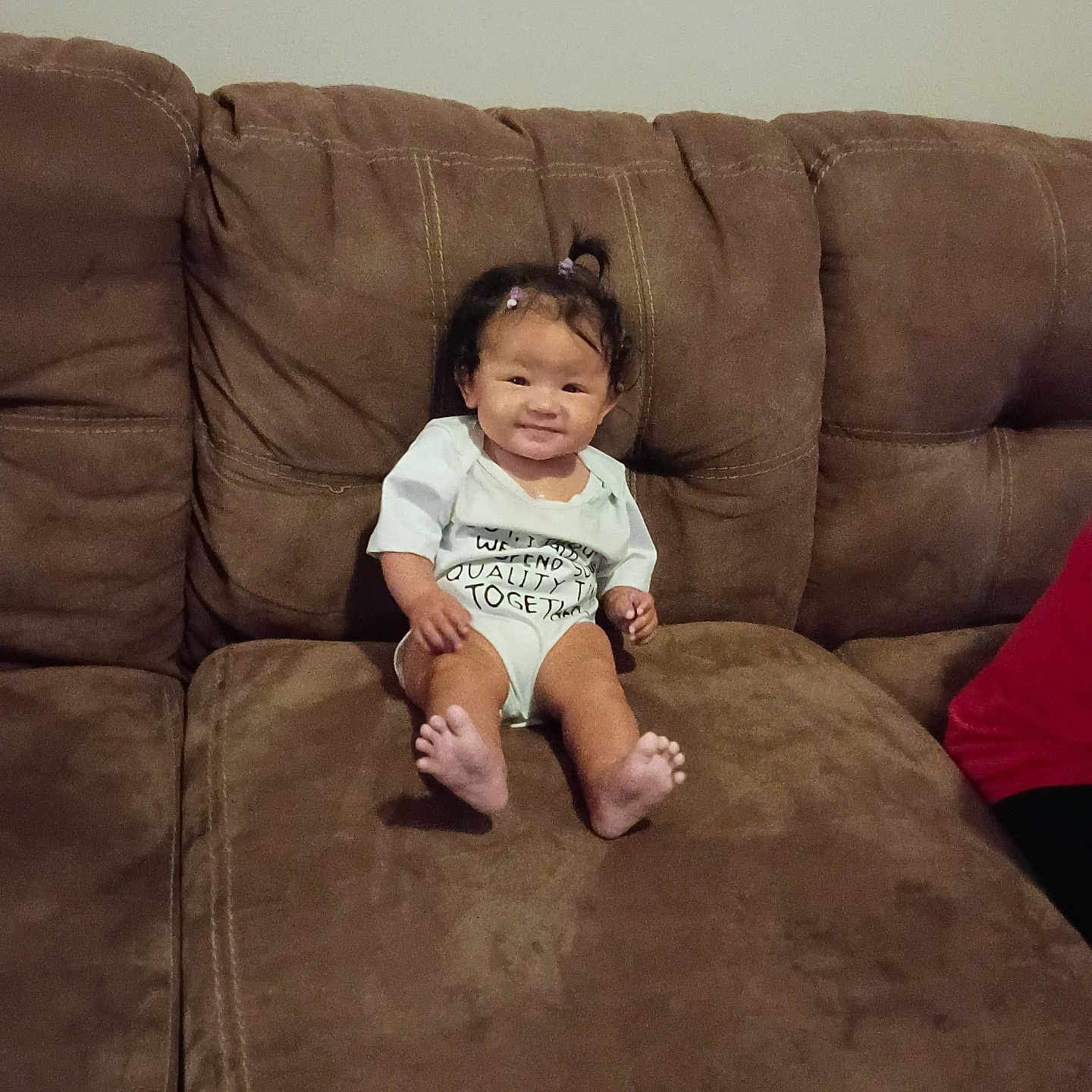 Kinsliegh is registered to the contest to win money with this photo: baby, child, smile, couch, sofa, brown, indoors, person, hair, pigtails, clothing, feet, sitting, furniture, living_room, cute, happy, young, infant, casual