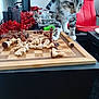 kitten, cat, chessboard, chess_pieces, table, red_chair, indoor, decorations, wooden, furniture, pet, animal, curious, playful, black_table, living_room, home, cozy, small_animal, domestic