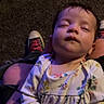 baby, sleeping, floral_outfit, tattoo, hand, sneakers, carpet, person, child, indoor, relaxing, peaceful, cute, infant, portrait, human, clothing, closeup, resting, casual