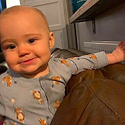 Ember joined the competition — help win amazing prizes! arm, baby, child, couch, cozy, curious, face, fox_print, furniture, head, home, indoor, leather, pajamas, person, radiator, sleepsuit, smiling, warm_lighting, young_child