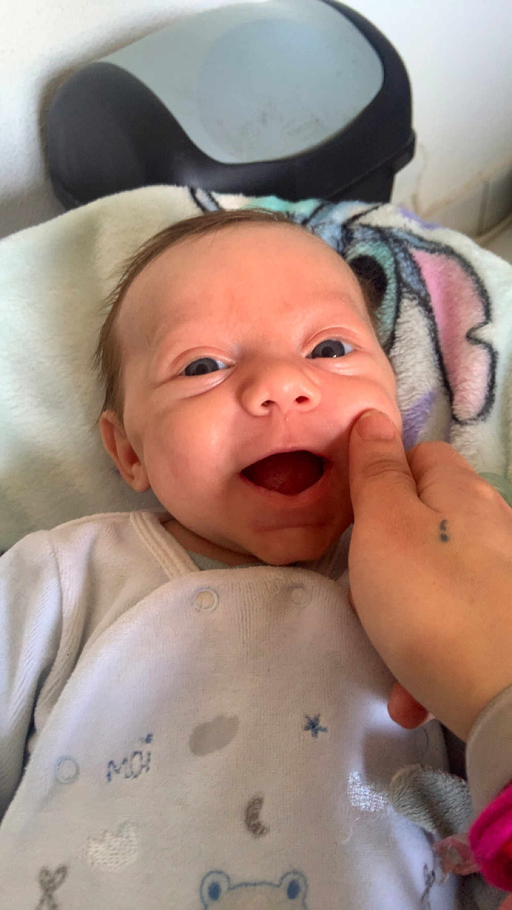 Maël participe au concours pour gagner de l'argent avec cette photo : baby, infant, smiling, face, hand, blanket, clothing, onesie, tattoo, cheek, happy, indoor, person, young_child, cute, expression, skin, fingertip, closeup, comfort
