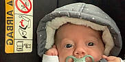 Maël a rejoint le concours — aidez-le/la à gagner de superbes lots ! baby, car_seat, pacifier, winter_clothing, hood, stars_pattern, infant, child, seatbelt, person, indoor, car_interior, cute, warm_clothing, face, head, eyes, hand, small_child, jacket