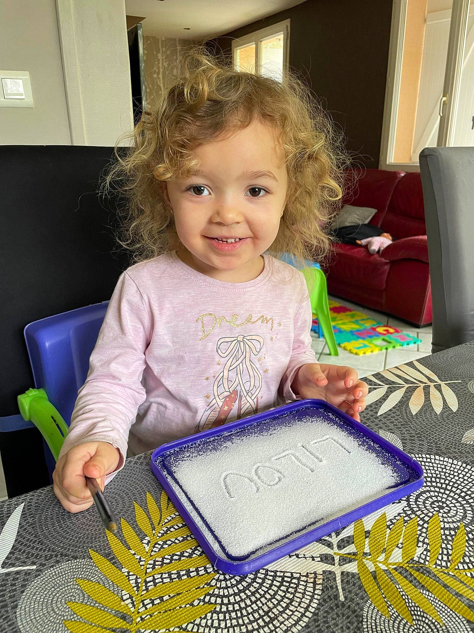 Lilou a rejoint le concours — aidez-le/la à gagner de superbes lots ! art, baby_toddler_clothing, chair, child, couch, flooring, fun, gadget, happy, home_appliance, joy, living_room, pattern, person, picture_frame, purple, room, sitting, smile, t_shirt