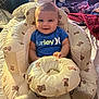 baby, smiling, blue_shirt, hurley, baby_chair, teddy_bear_pattern, cushion, indoor, television, remote_control, blanket, bed, happy, person, infant, clothing, head, face, seated, room