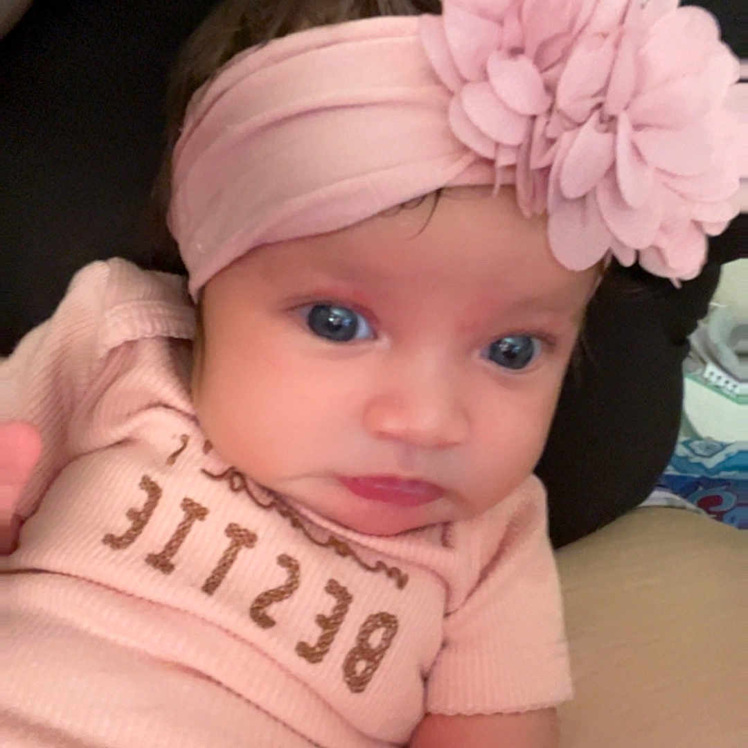 Arielynn is registered to the contest to win money with this photo: apparel, arm, baby, blue_eyes, child, closeup, comfort, cute, flower, hand, indoor, infant, person, pink_headband, portrait, resting, skin, soft_clothing, tattoo, young_baby