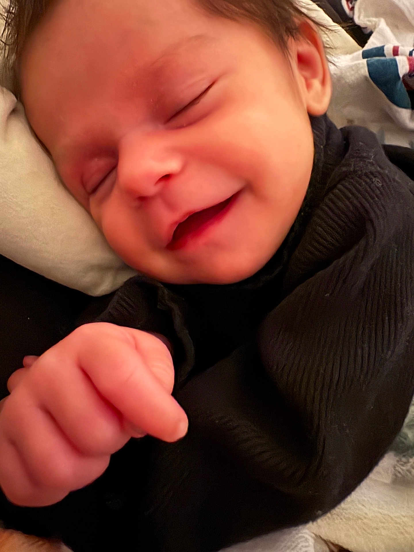 Sabrina is registered to the contest to win money with this photo: baby, infant, sleeping, smile, hand, face, black_clothing, cozy, closeup, peaceful, newborn, skin, cute, child, portrait, soft, resting, young, human, indoors