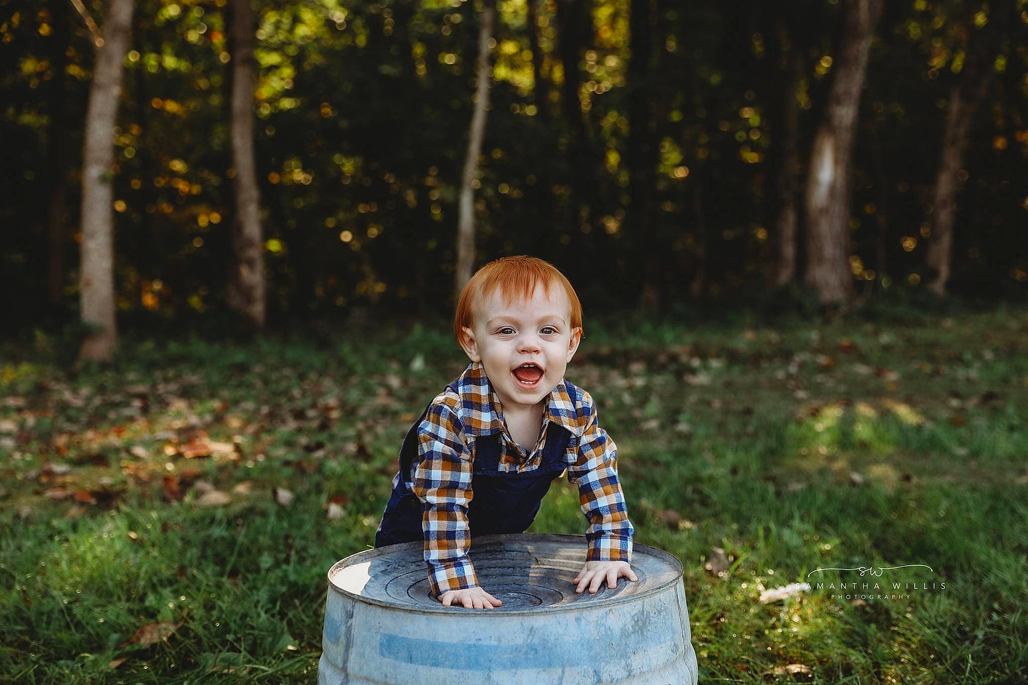 Beckett is registered to the contest to win money with this photo: automotive_tire, baby, child, city, deciduous, forest, fun, grass, happy, leisure, people_in_nature, person, plant, recreation, sitting, smile, toddler, tree, trunk, wood