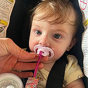 Ensley joined the competition — help win amazing prizes! baby, infant, pacifier, car_seat, warning_label, seat_belt, hand, close_up, portrait, eyes, face, hair, bottle, pacifier_clip, clothing, strap, buckle, skin, sitting, cute