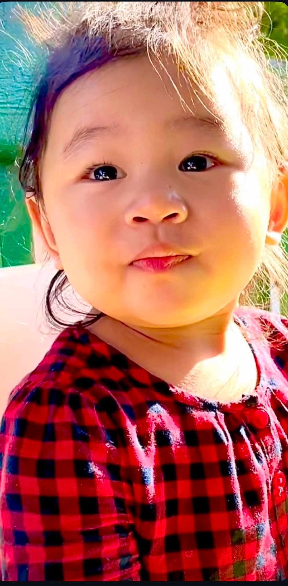 Rachel is registered to the contest to win money with this photo: child, toddler, portrait, face, eyes, hair, cheeks, expression, cute, plaid_dress, red_clothing, close_up, outdoor, sunlight, backlit, pursed_lips, young_child, skin, shoulder, happy