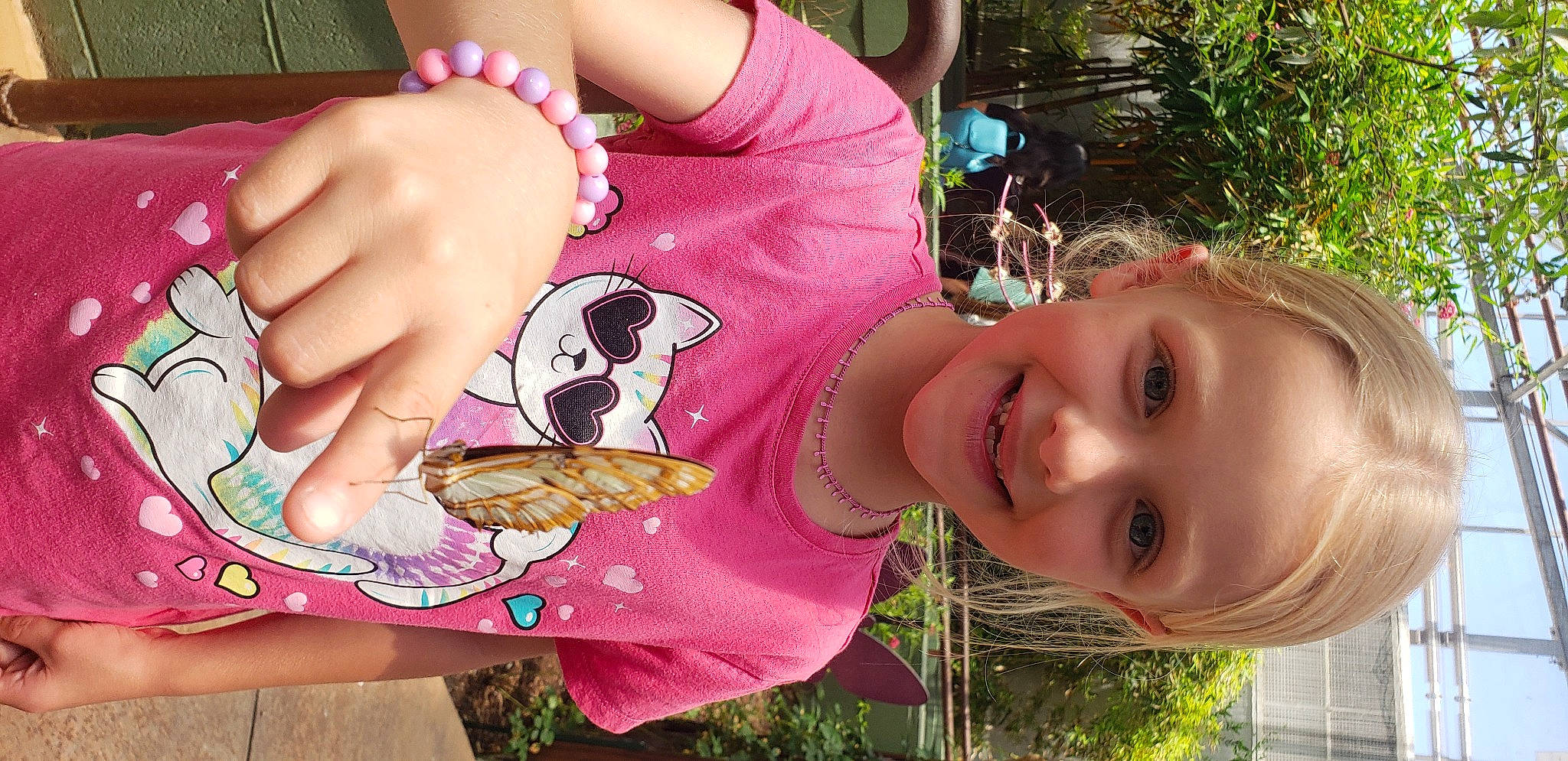 Eva is registered to the contest to win money with this photo: baby_toddler_clothing, child, finger, food, food_craving, grass, green, hand, happy, joy, mouth, nail, organ, person, pink, plant, sharing, skin, smile, summer