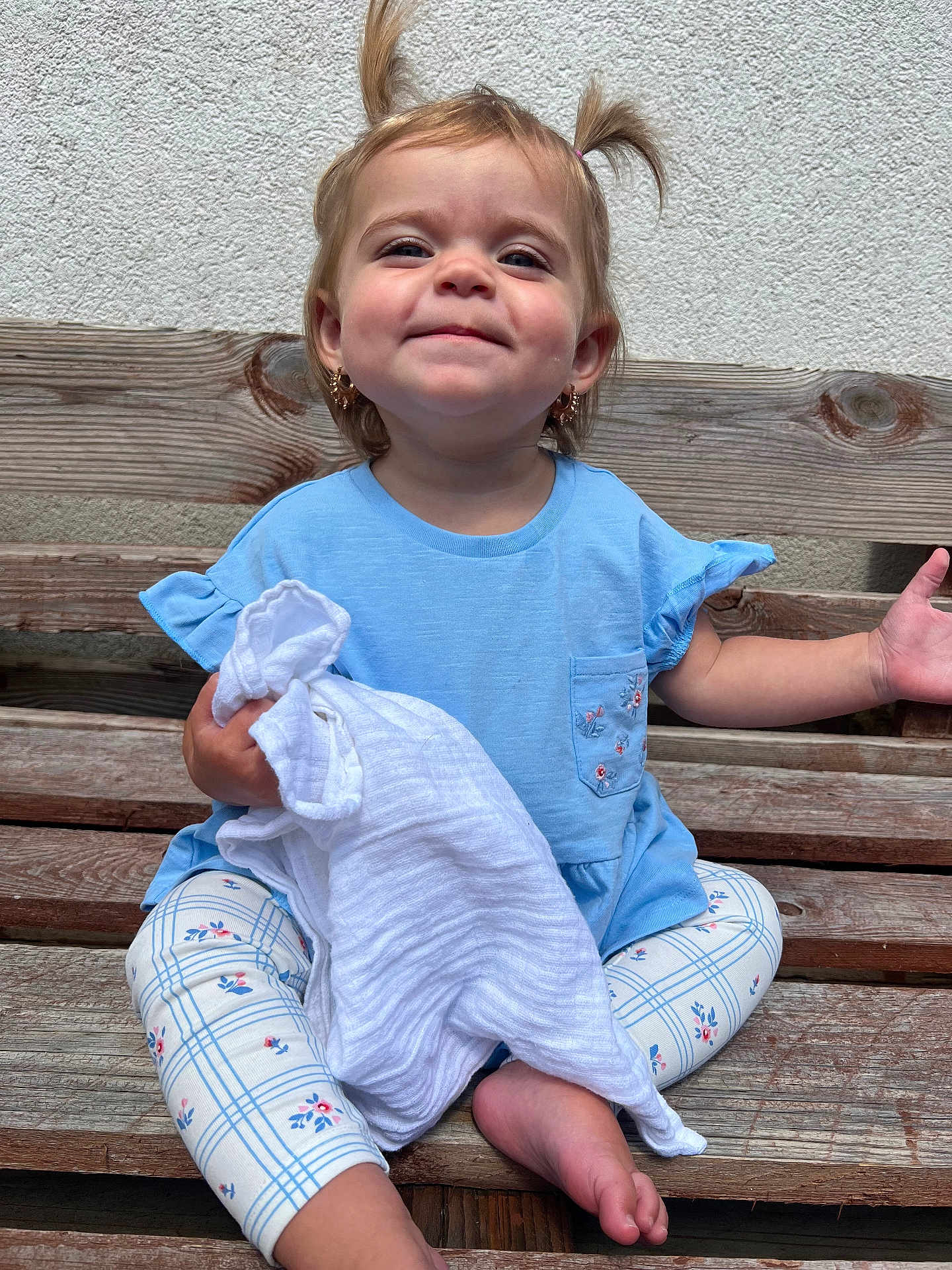 Adorabella is registered to the contest to win money with this photo: toddler, child, bench, blue_shirt, blanket, leggings, pigtails, smile, earrings, outdoor, wood, wall, happy, sitting, barefoot, person, cute, texture, young_child, portrait