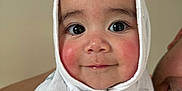 Daniela is registered to the contest to win money with this photo: baby, child, face, smile, person, wrapped, cloth, white, rosy_cheeks, eyes, portrait, indoor, human, cute, head, closeup, expression, warmth, happy, parent