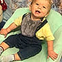 Brayden is registered to the contest to win money with this photo: toddler, child, smiling, denim_overalls, yellow_shirt, bib, mint_green_chair, plush_toy, snowman, winter_theme, blanket, indoor, happy, sitting, cute, face, sock, baby, portrait, cozy