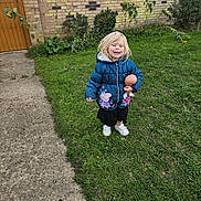 Ellah joined the competition — help win amazing prizes! child, grass, jacket, doll, smile, outdoor, sunflowers, brick_wall, blonde_hair, casual_clothing, white_shoes, greenery, happy, person, nature, playful, daylight, young, toy, garden
