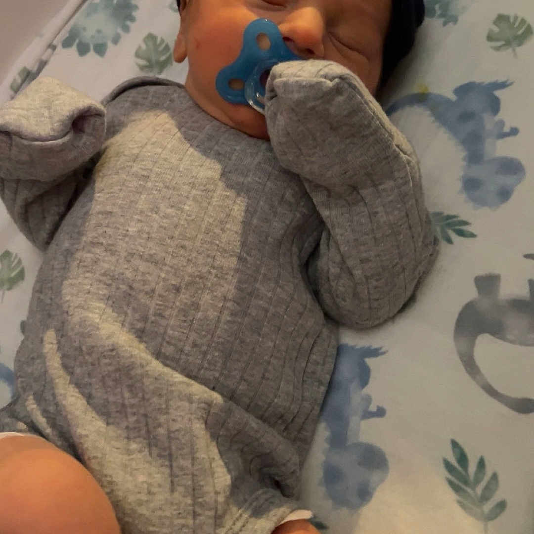 Kyzier is registered to the contest to win money with this photo: baby, sleeping, pacifier, gray_clothing, black_cap, blanket, patterned_sheet, infant, peaceful, indoors, soft_lighting, resting, cute, newborn, child, cozy, small, person, wrapped, toddler