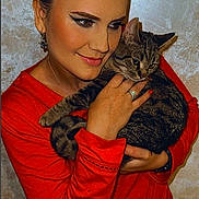 Kity participe au concours pour gagner de l'argent avec cette photo : woman, cat, tabby_cat, red_clothing, portrait, smile, face, hand, earrings, makeup, indoor, comfort, affection, pet, animal, holding, closeup, warm_lighting, background, cuddle