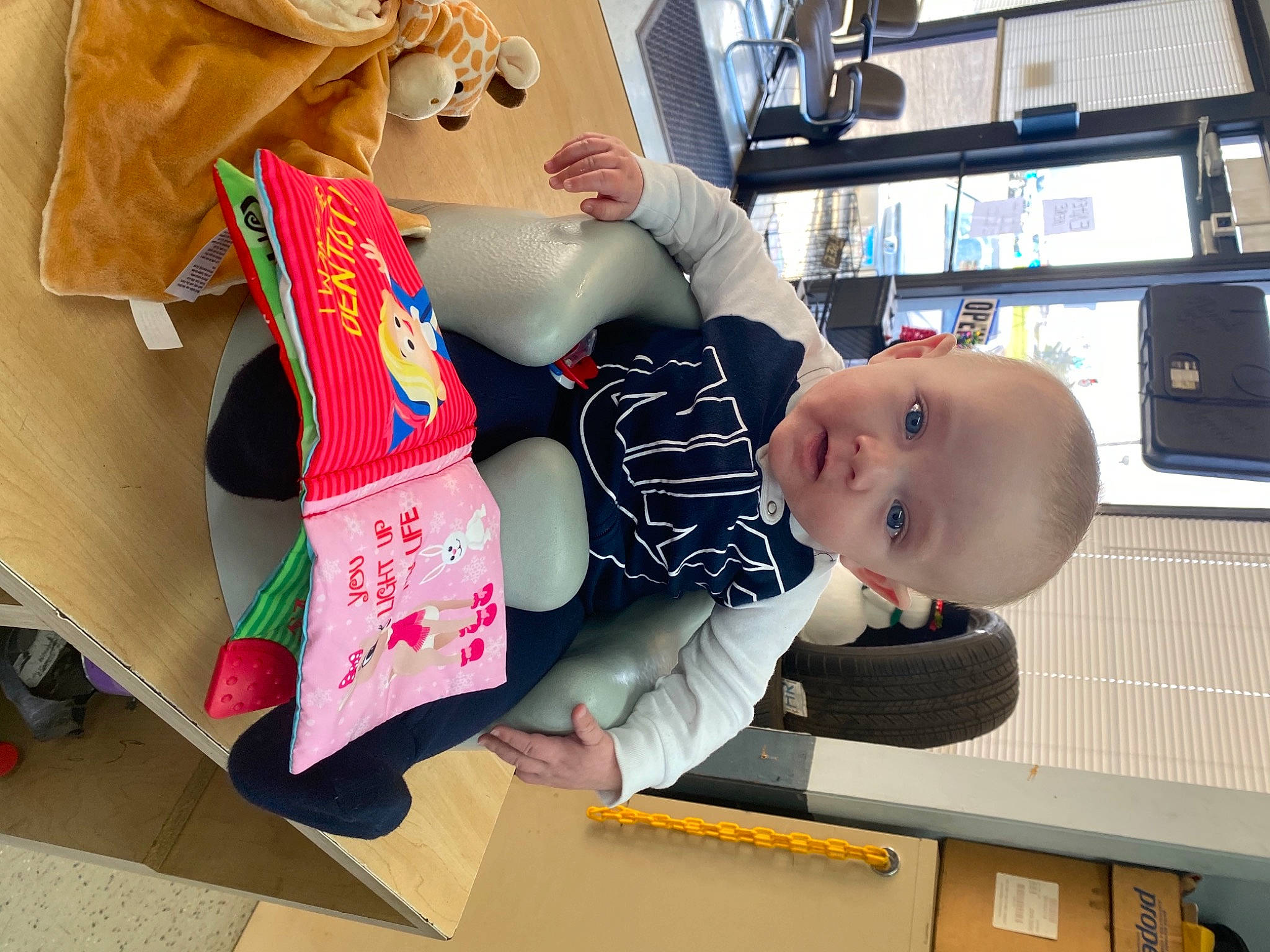 Kayden is registered to the contest to win money with this photo: baby, baby_products, baby_toys, carmine, child, fun, happy, headgear, mammal, person, play, room, shelf, shelving, sitting, smile, stuffed_toy, t_shirt, toddler, toy