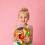 Jade participe au concours pour gagner de l'argent avec cette photo : child, girl, blonde_hair, smile, happy, holding, ball, colorful, shiny, top_knot, pink_background, portrait, studio, cute, innocence, joy, casual_clothing, young, person, playful
