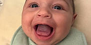 Robert joined the competition — help win amazing prizes! baby, smiling, face, bib, clothing, infant, happy, mouth_open, tongue, cheeks, skin, head, person, closeup, expression, cute, child, indoors, soft_background, text_on_clothing