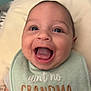baby, smiling, face, bib, clothing, infant, happy, mouth_open, tongue, cheeks, skin, head, person, closeup, expression, cute, child, indoors, soft_background, text_on_clothing