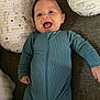 Robert is registered to the contest to win money with this photo: baby, smiling, onesie, blue_clothing, couch, pillow, animal_pattern, happy, infant, indoor, face, child, cute, cozy, blanket, fabric, home, relaxing, lying_down, comfort