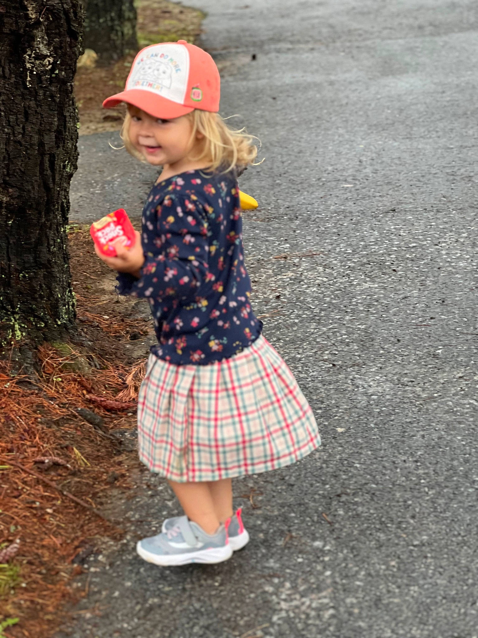 Brynn is registered to the contest to win money with this photo: asphalt, baseball_cap, cap, fun, grass, hat, headwear, pattern, people_in_nature, person, plaid, plant, recreation, shoe, sleeve, sneakers, standing, tartan, textile, toddler