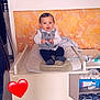 Kayden participe au concours pour gagner de l'argent avec cette photo : baby, child, changing_table, cushion, vest, shirt, indoor, orange_wallpaper, heart_emoji, person, footwear, socks, cabinet, storage, diapers, clothing, furniture, smile, face, toy
