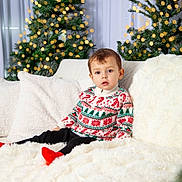 Kayden participe au concours pour gagner de l'argent avec cette photo : toddler, child, christmas_sweater, holiday, festive, couch, pillow, blanket, christmas_tree, lights, indoor, cozy, cute, portrait, smiling, red_socks, winter, decorations, home, celebration