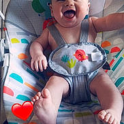 Liam joined the competition — help win amazing prizes! baby, child, smiling, happy, infant, baby_rocker, seat, colorful, patterned, animal_print, indoor, floor_tiles, foot, hand, person, cute, joyful, baby_clothing, strap, playful